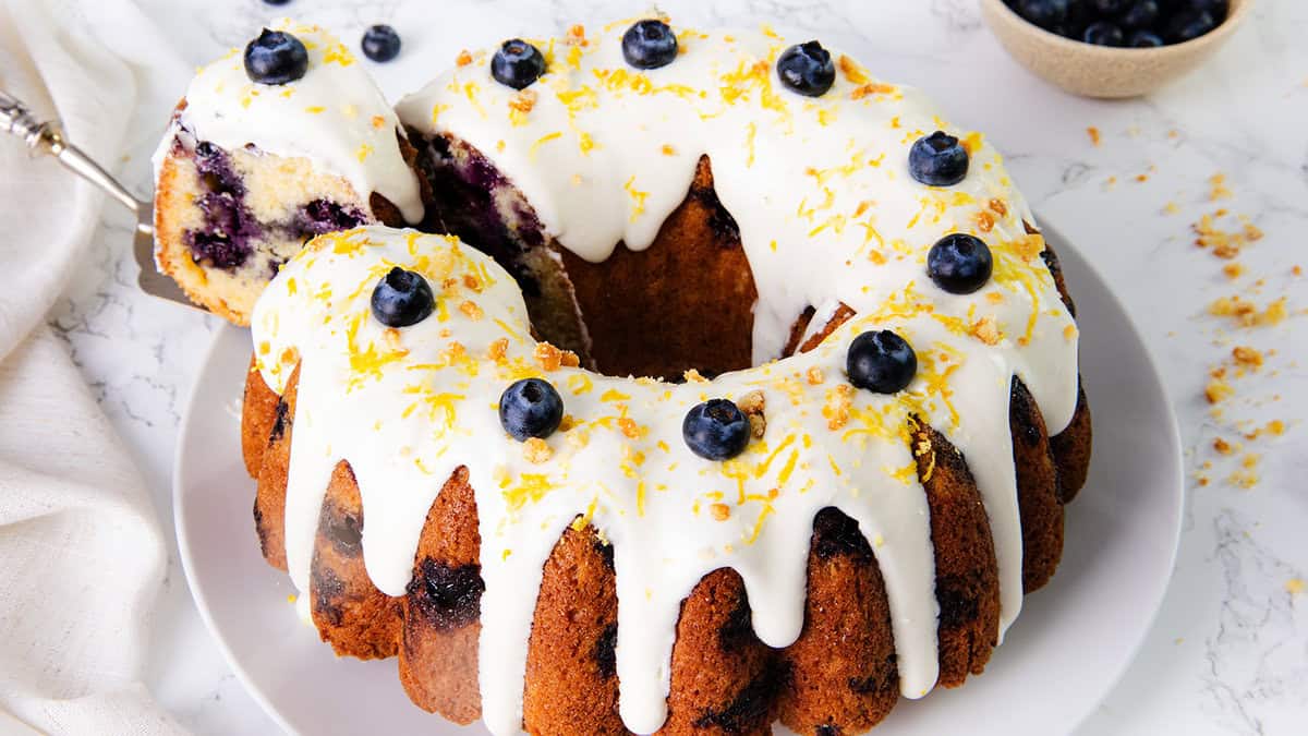 A lemon blueberry cake topped with white frosting and blueberries.