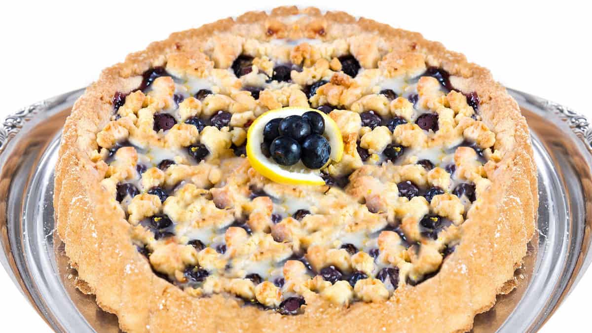 A close up image of a freshly baked blueberry pie topped with shortbread crumbs.