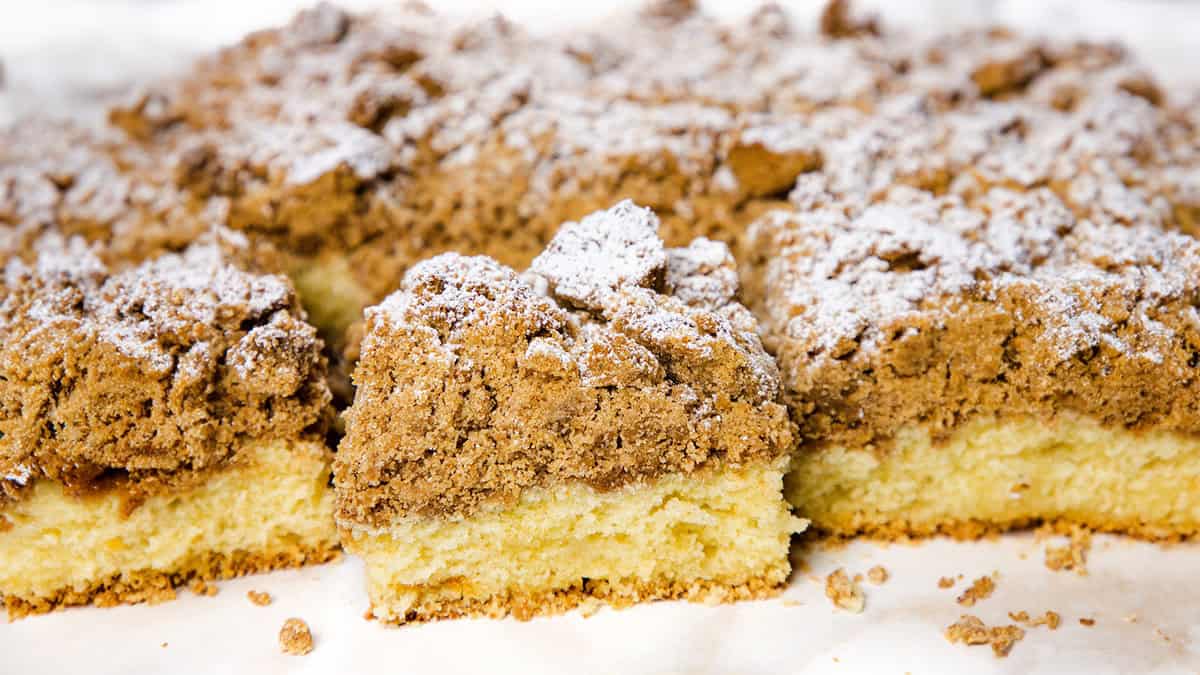 A crumbled coffee cake from which a slice has been cut.