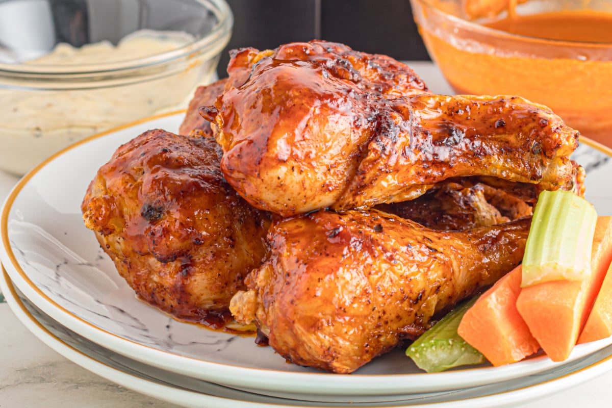 Glazed roasted chicken thighs served with celery and carrot sticks on a plate.