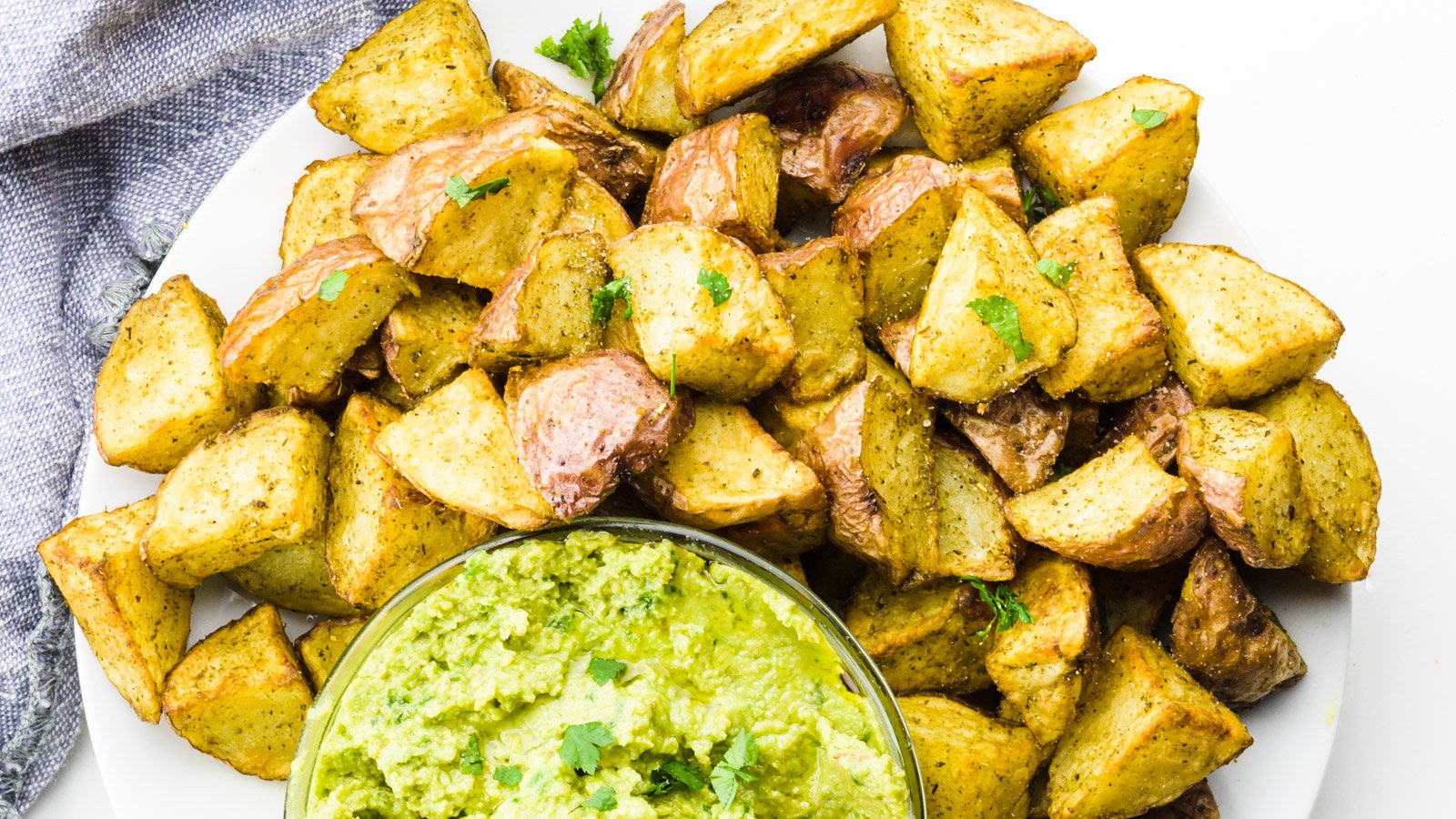 Looking down at a plate of roasted potatoes with a bowl of salsa verde for dipping.