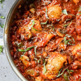 Overhead view of skillet chicken cacciatore recipe with basil for garnish