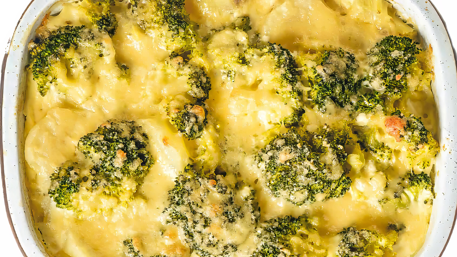 A close up image of a skillet filled with broccoli and cauliflower casserole.