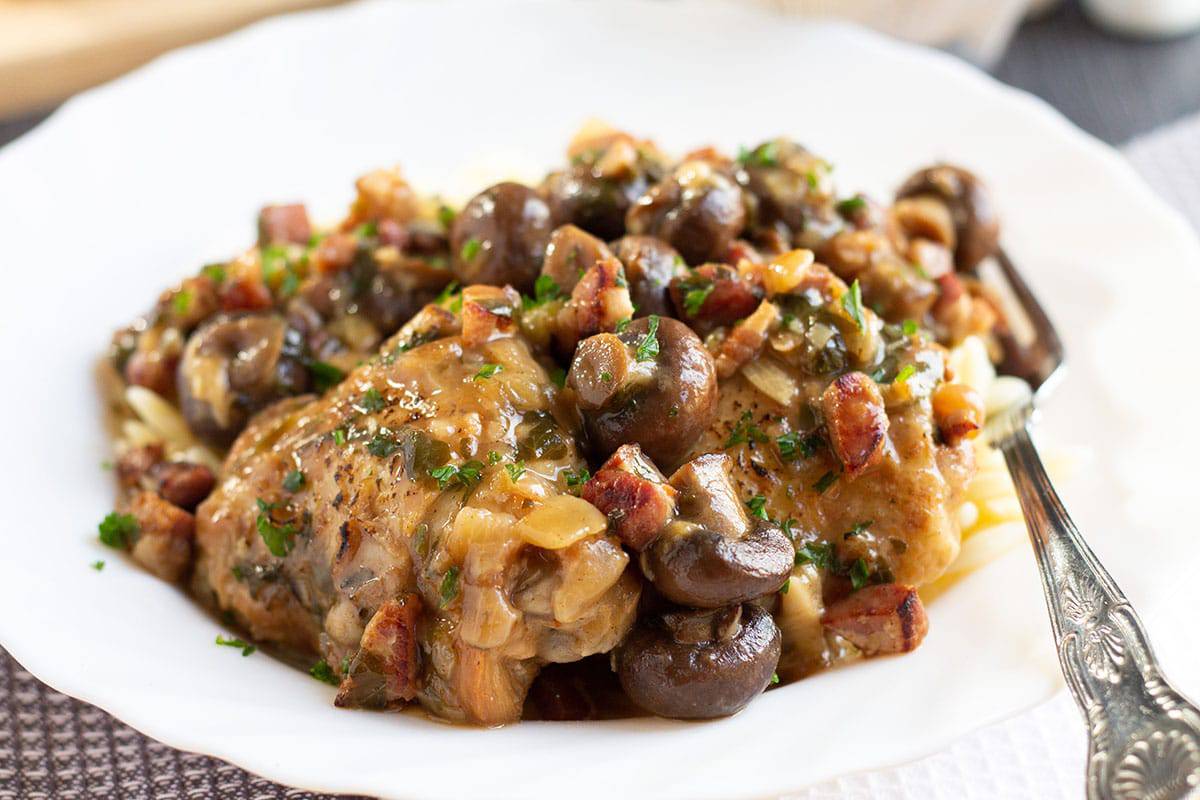 Chicken with sherry mushroom sauce stacked on a white plate