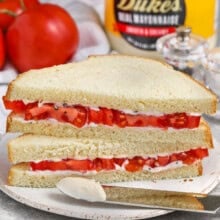 Classic tomato sandwich with mayonnaise on the sandwich and on a knife.