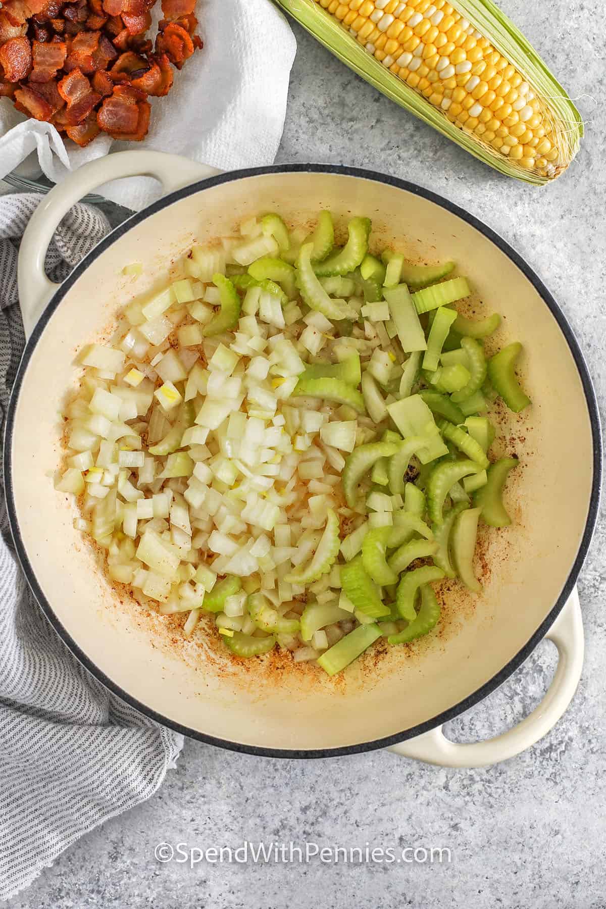 Adding onions and celery to the pot to make an easy homemade corn chowder