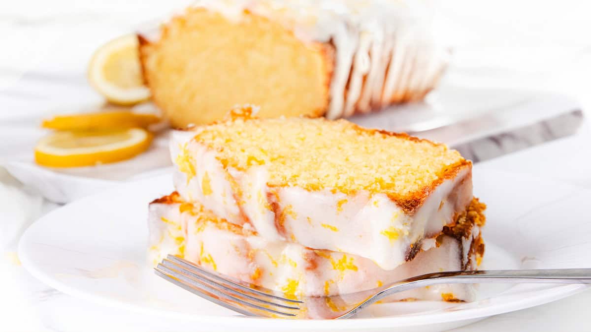 A sliced ​​lemon cake with icing and lemon zest.