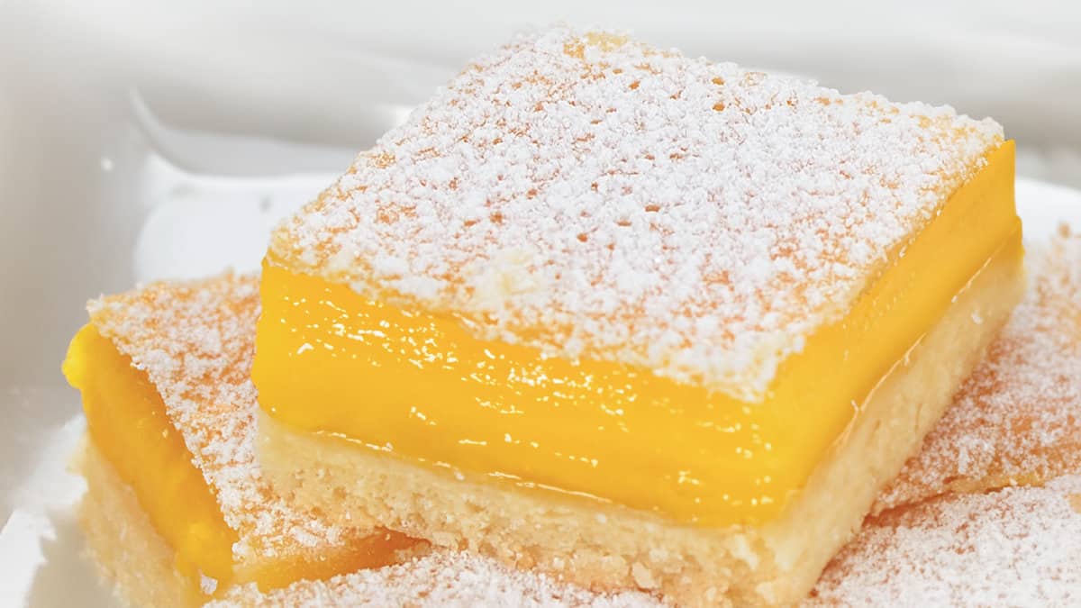 A close up image of a stack of lemon squares on a white plate.