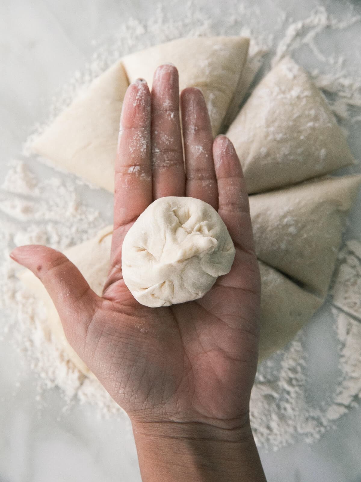 A ball of dough in the palm of a hand.