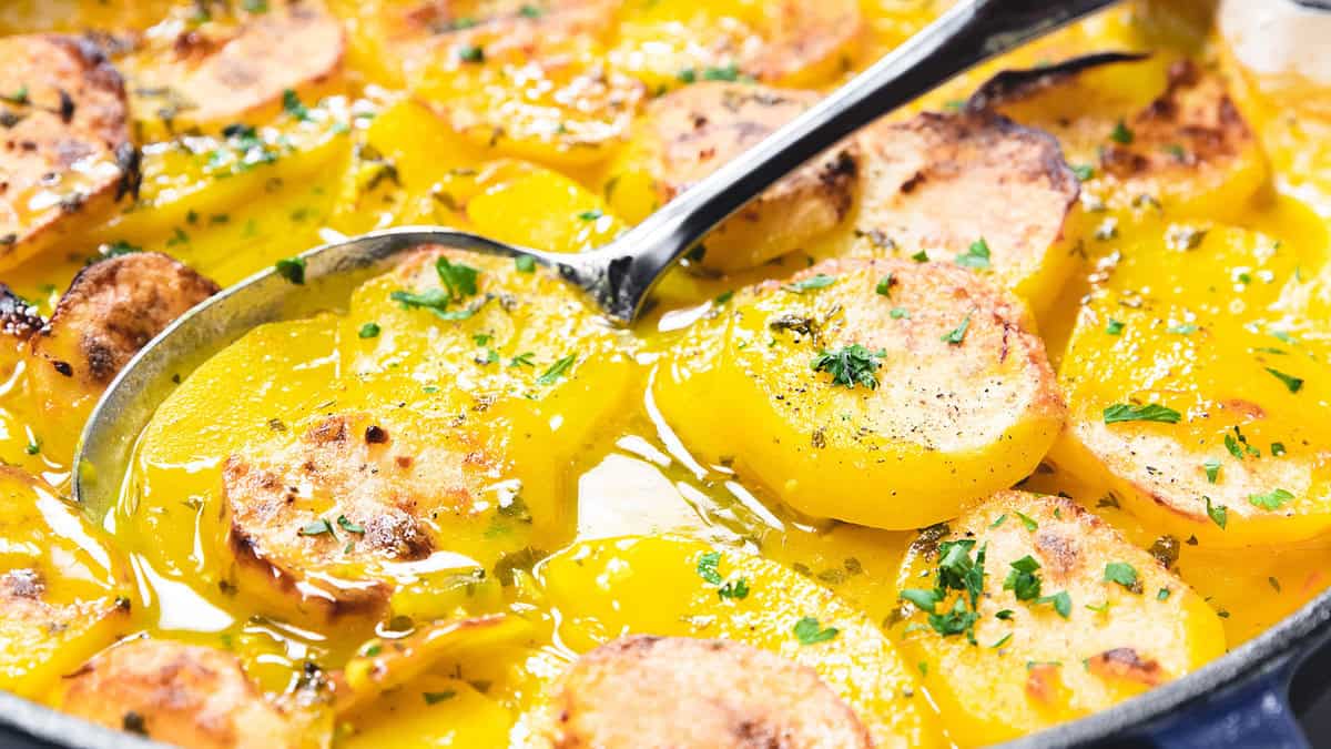 A spoonful of saffron potato casserole scooped out of a frying pan.