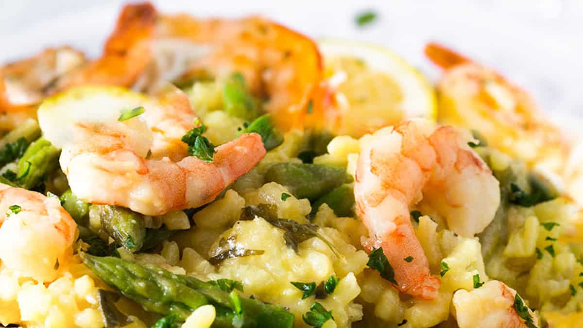 A plate filled with yellow rice, asparagus and plump shrimp.