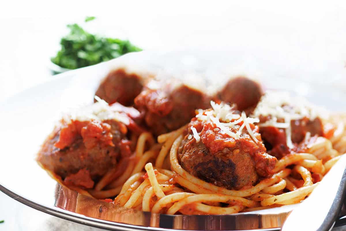 A close-up of spaghetti and meatballs on a plate with a fork.