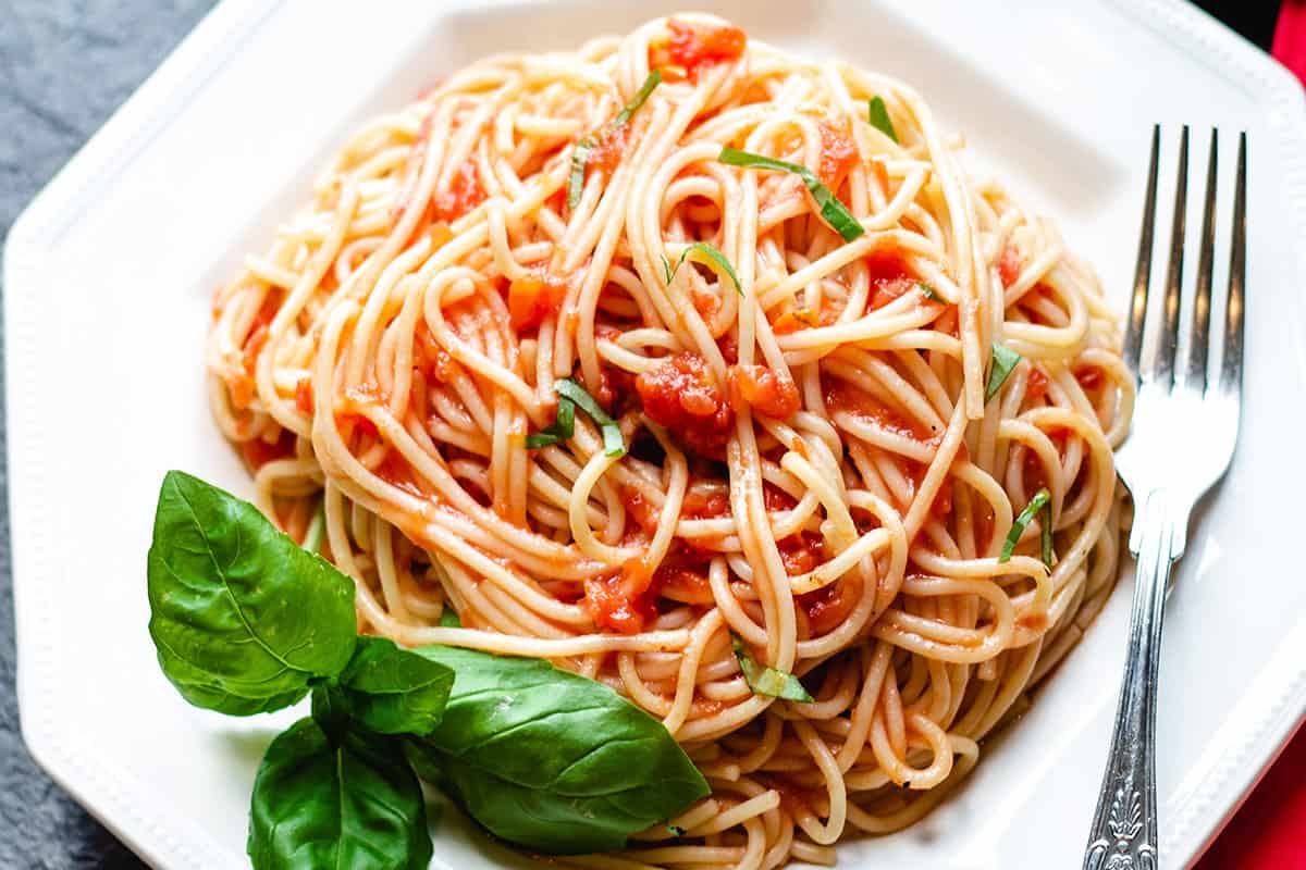 A photo taken from above of a plate of spaghetti with tomato sauce with a fork next to it.