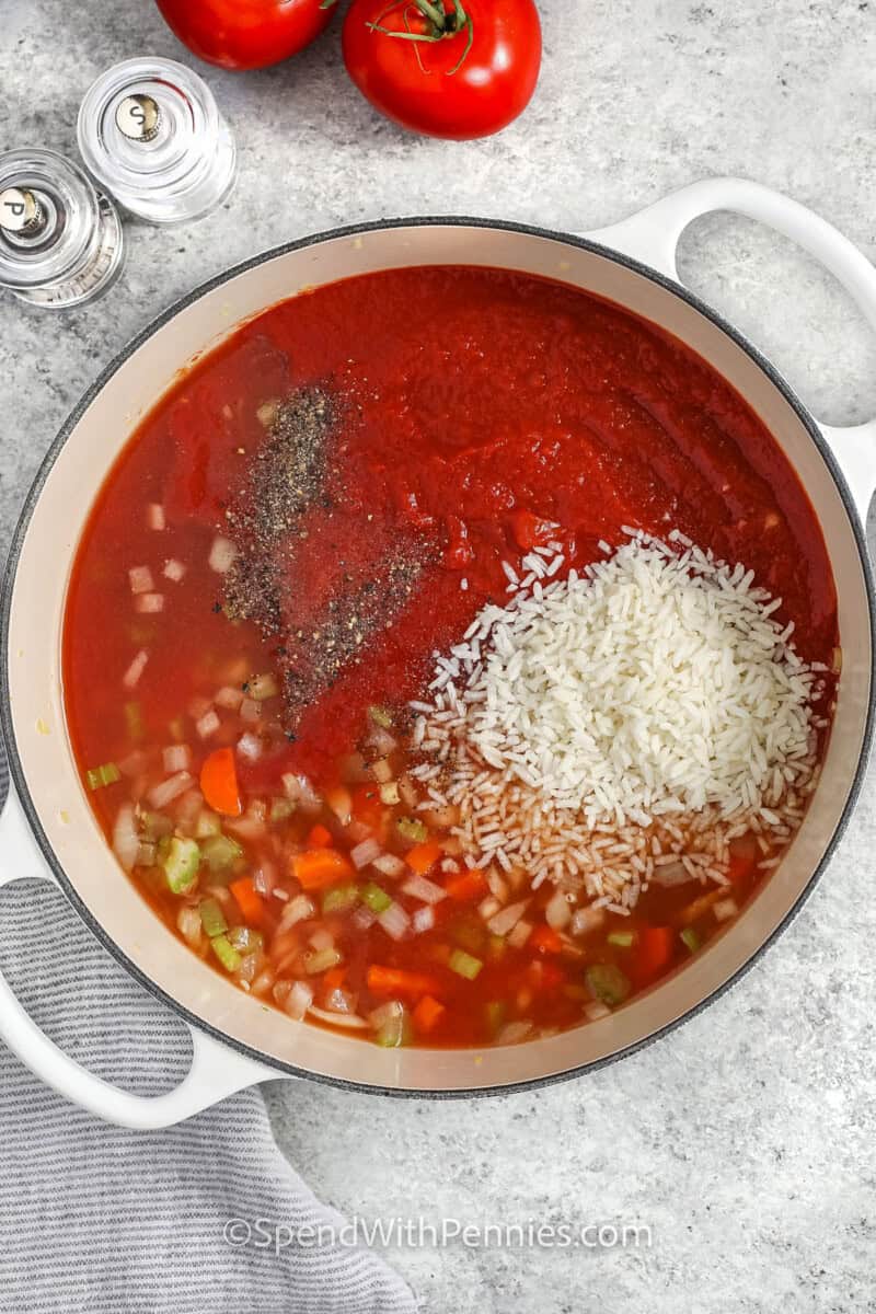 Adding rice, crushed tomatoes, broth and seasonings to the pot to make tomato soup