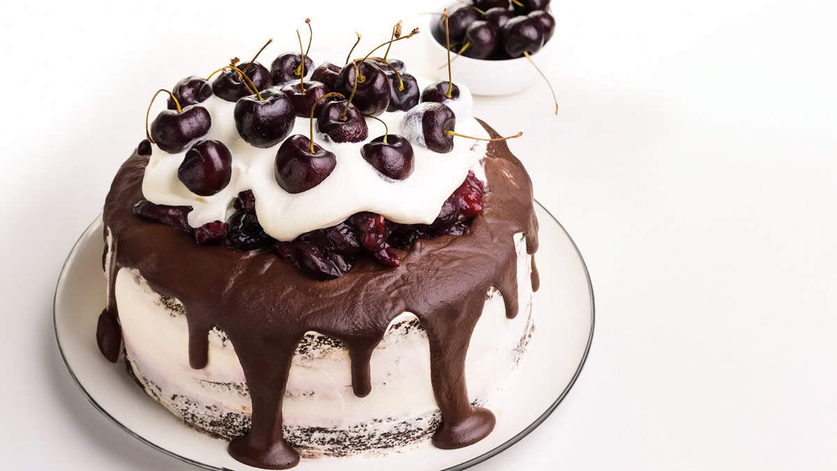 A vegan Black Forest cake topped with cherries and whipped cream.