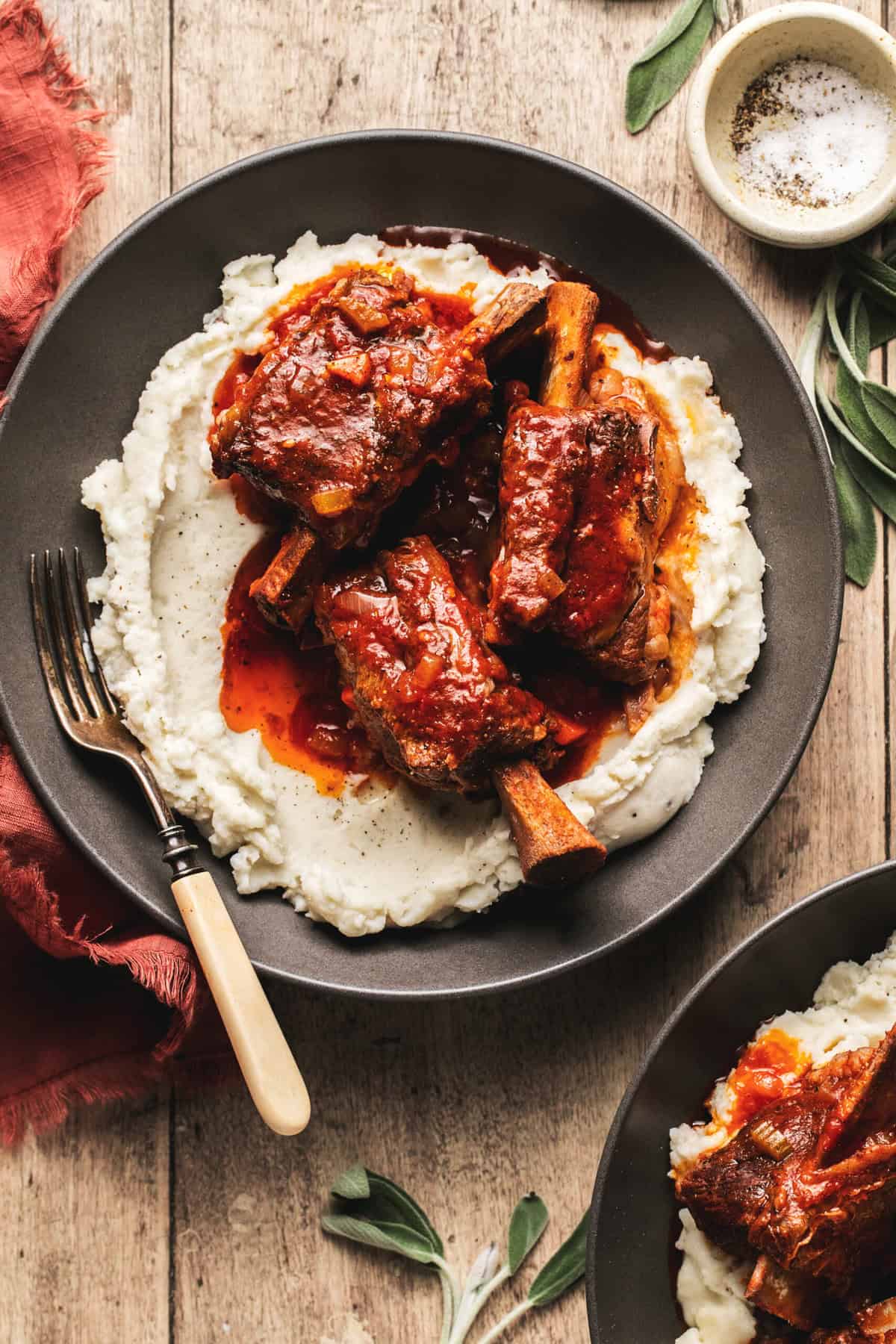 Overhead view of a plate of mashed potatoes topped with short ribs and gravy.