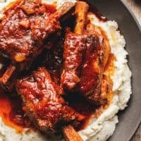 Beef ribs with gravy over mashed potatoes in a bowl