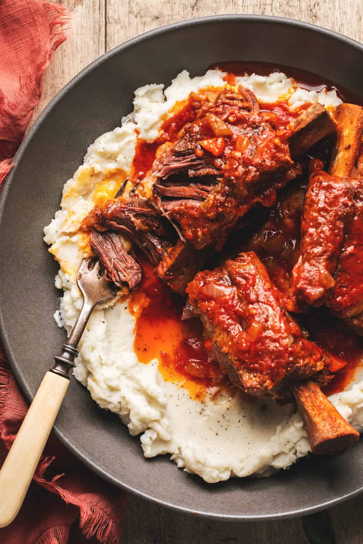 Meat torn with a fork from the short rib bone on top of potatoes