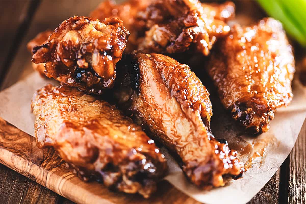 Chicken wings on a wooden block with dipping sauce in the bottom