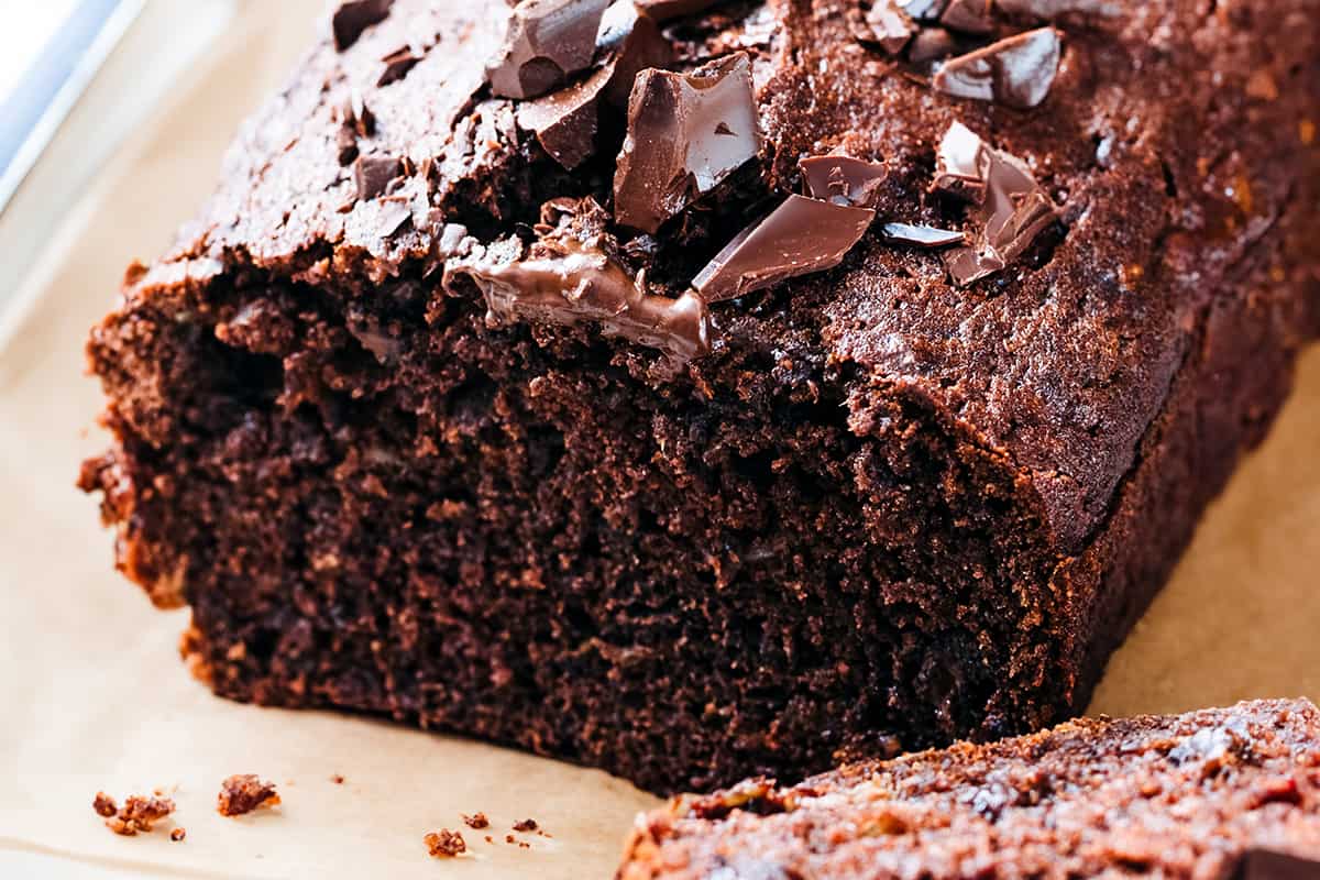 A close up image of a sliced ​​chocolate banana cake topped with crushed chocolate.