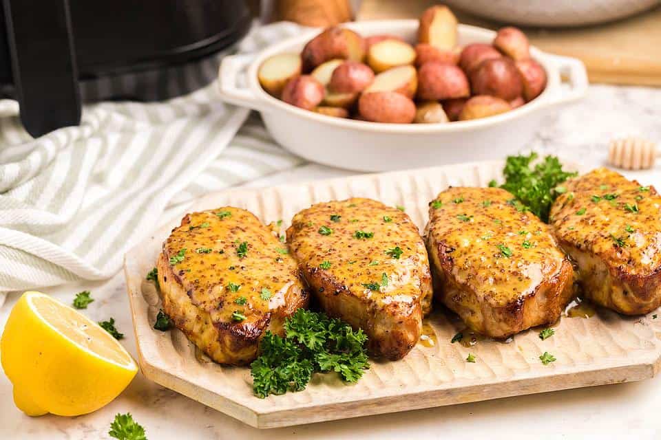 Air fryer honey mustard pork chops on a wooden board.