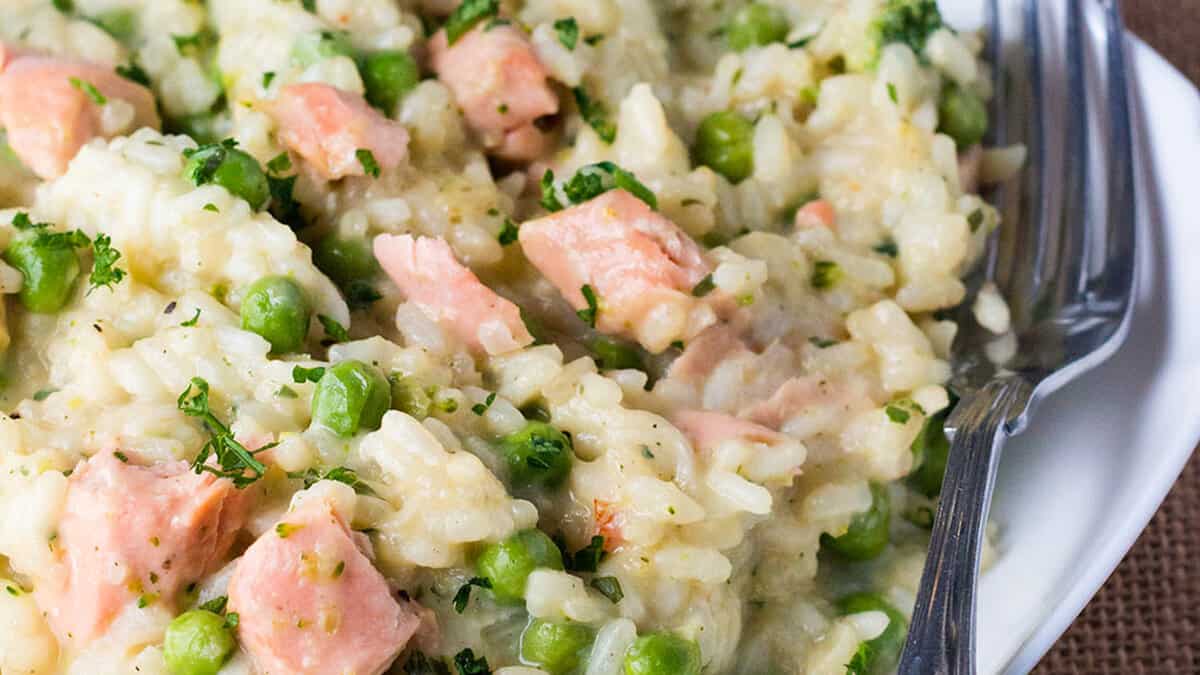 Easy Salmon and Pea Risotto on a white plate with a fork on the side.