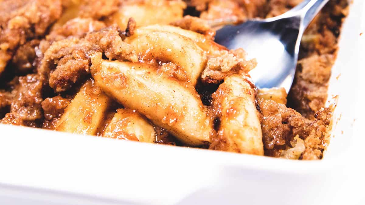 A plate full of baked apples and crumb topping.