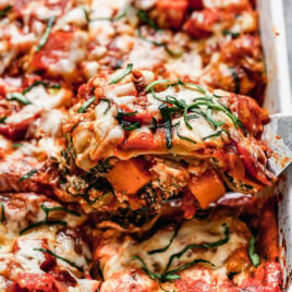 A piece of vegetable lasagna being cut from a plate.