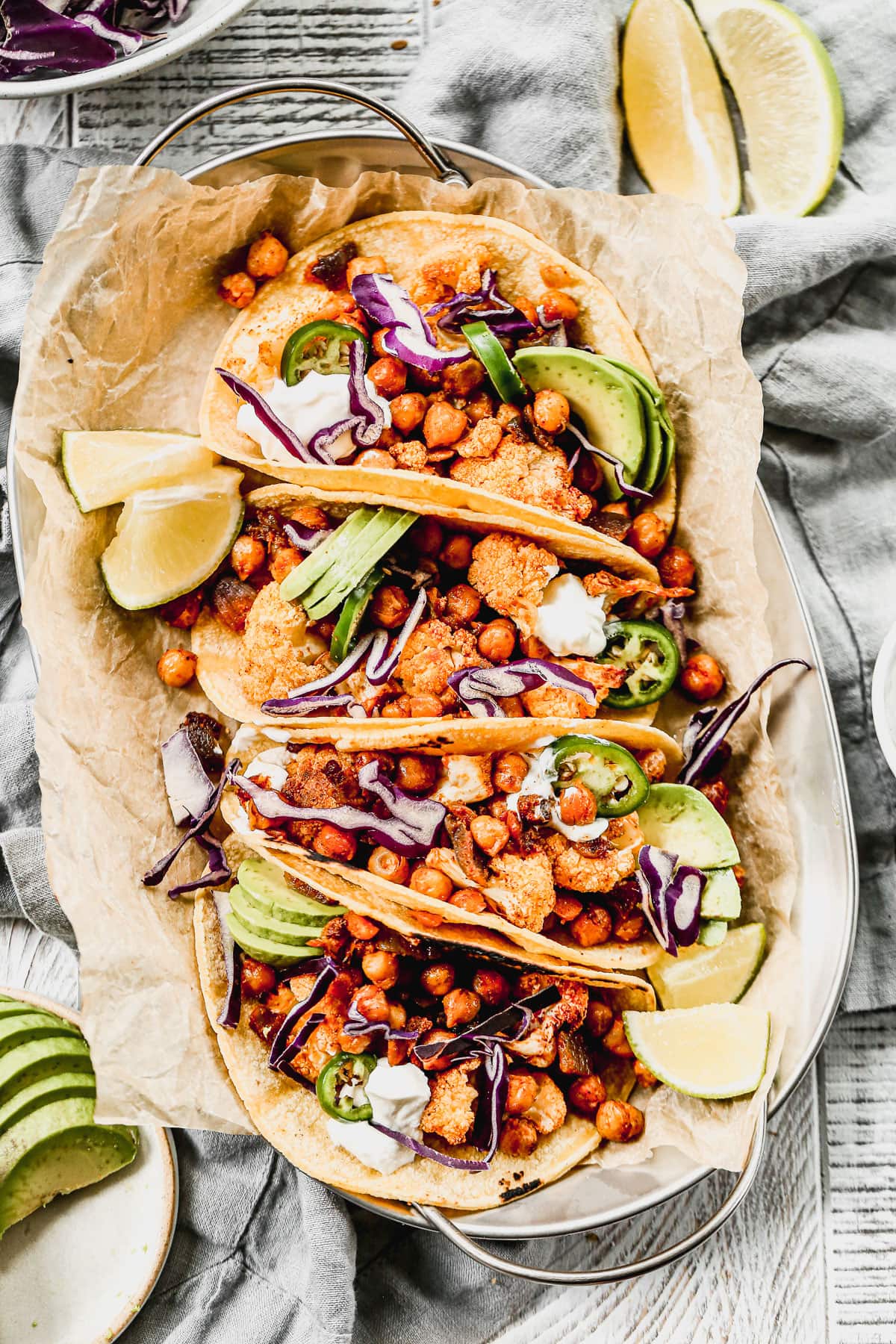 Chipotle cauliflower tacos on a plate with limes and avocado