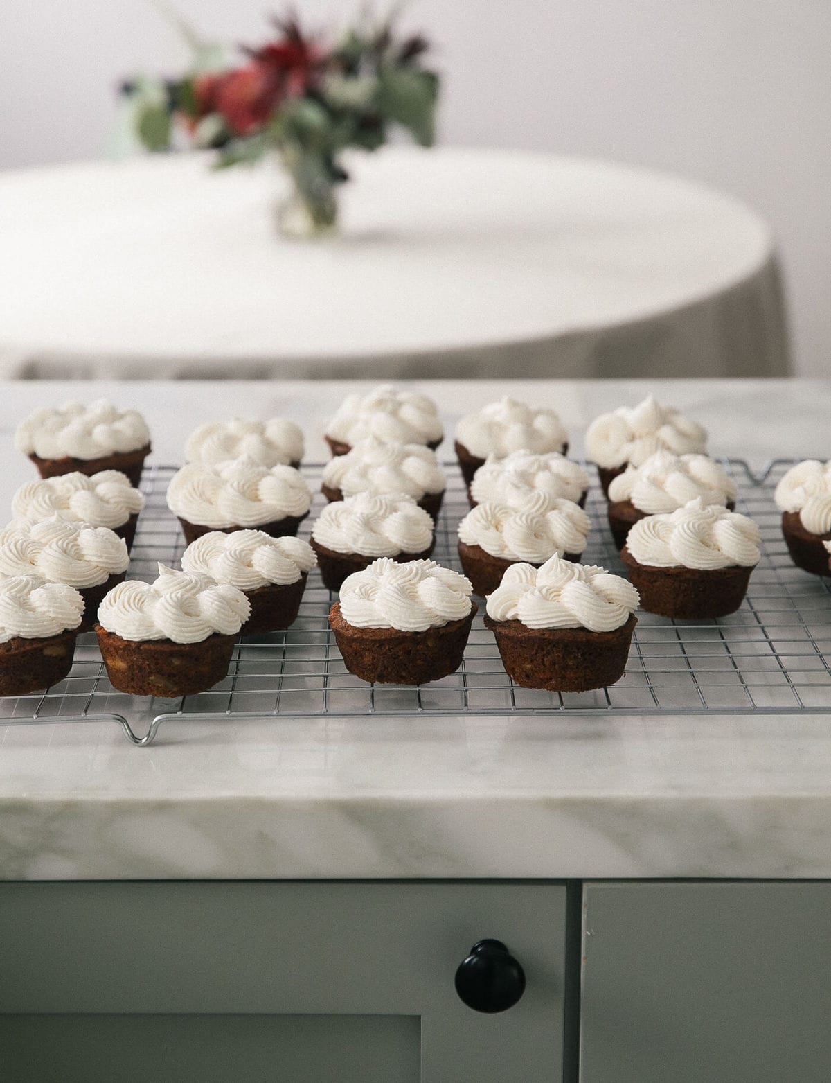 Cupcakes on a wire rack covered with frosting.