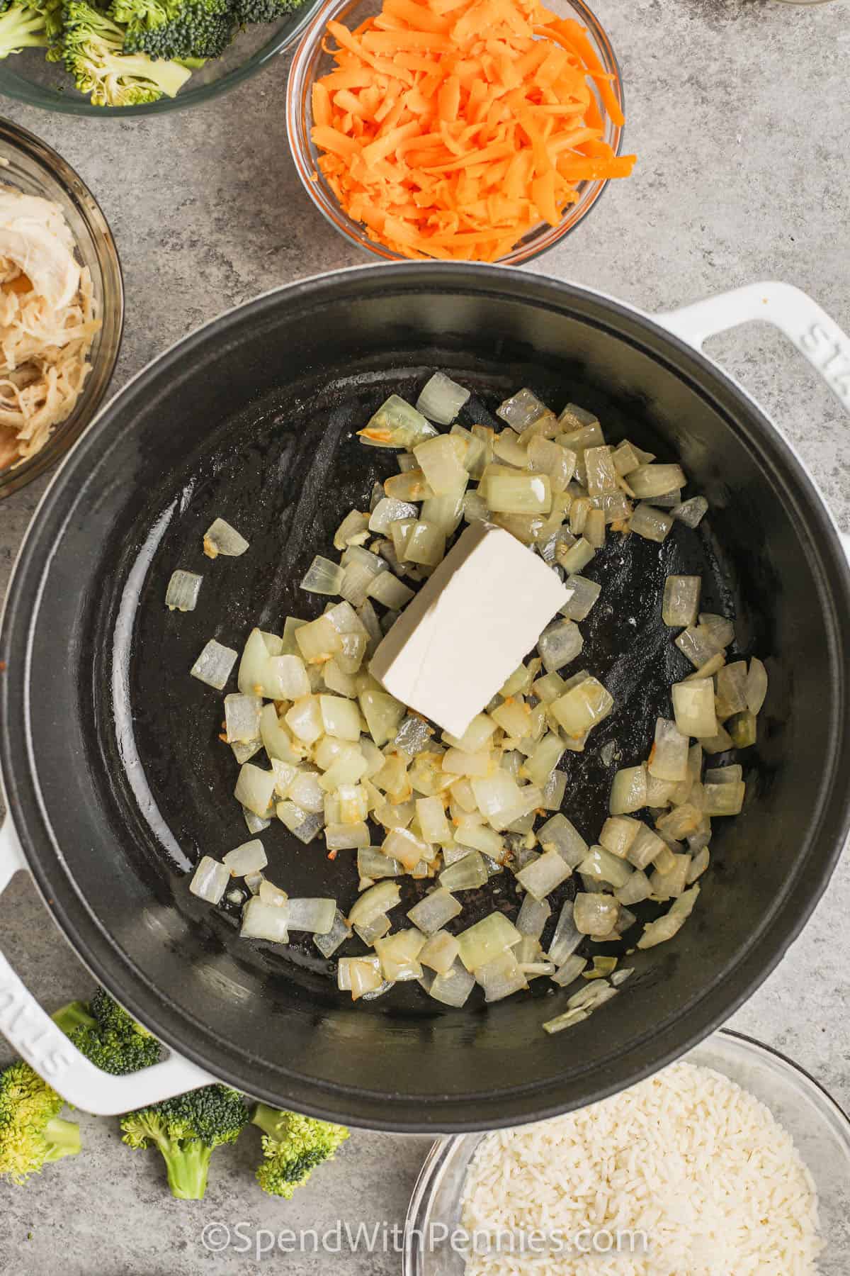 Adding cream cheese to cooked onions to make chicken and broccoli rice casserole