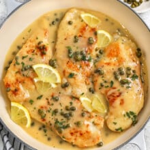 A pan of chicken piccata with lemon slices and capers