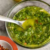 Chimichurri sauce in a glass bowl with a spoon