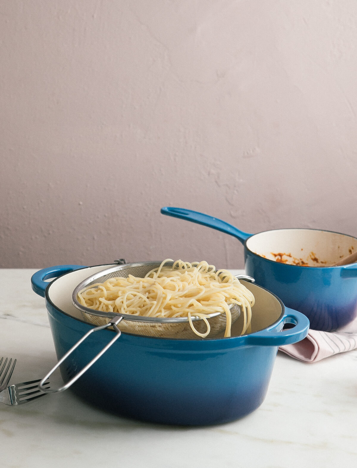 Pasta in a colander over a pot. 