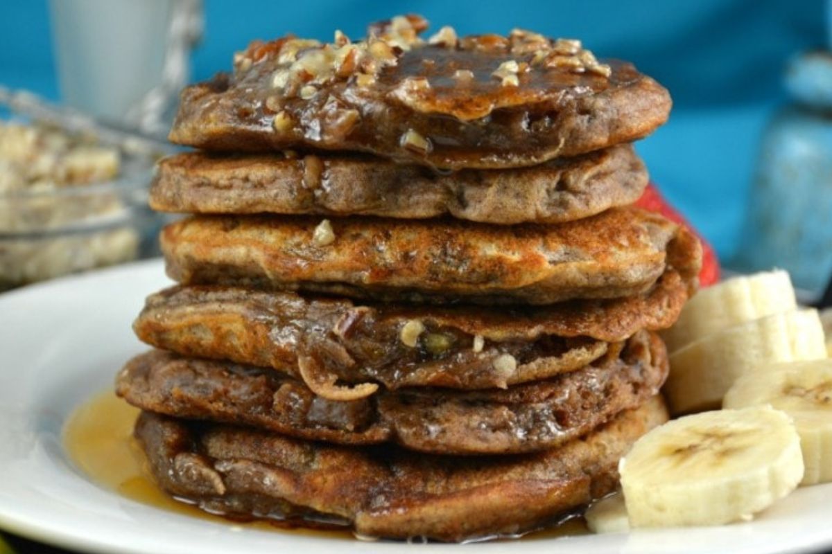 A stack of banana walnut pancake recipes with syrup on a plate.