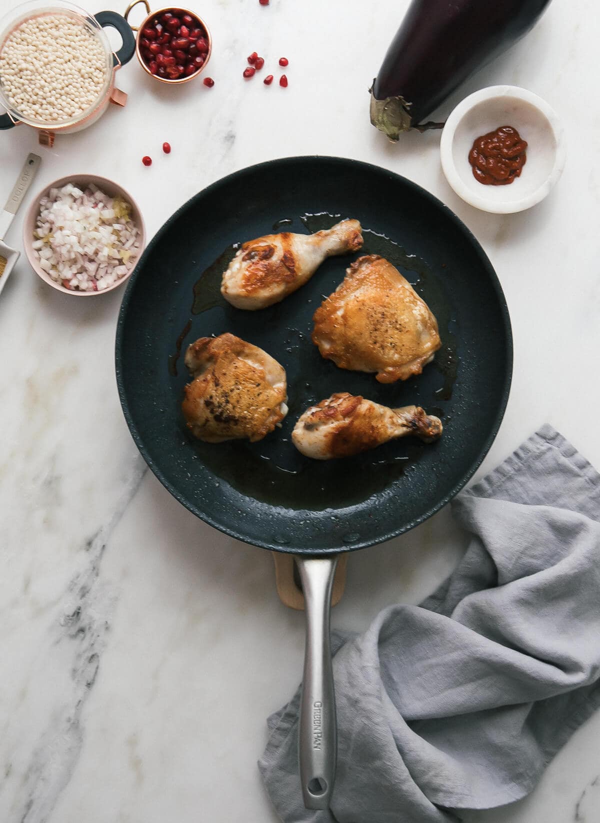 Overhead view of browned chicken thighs and drumsticks in a skillet.