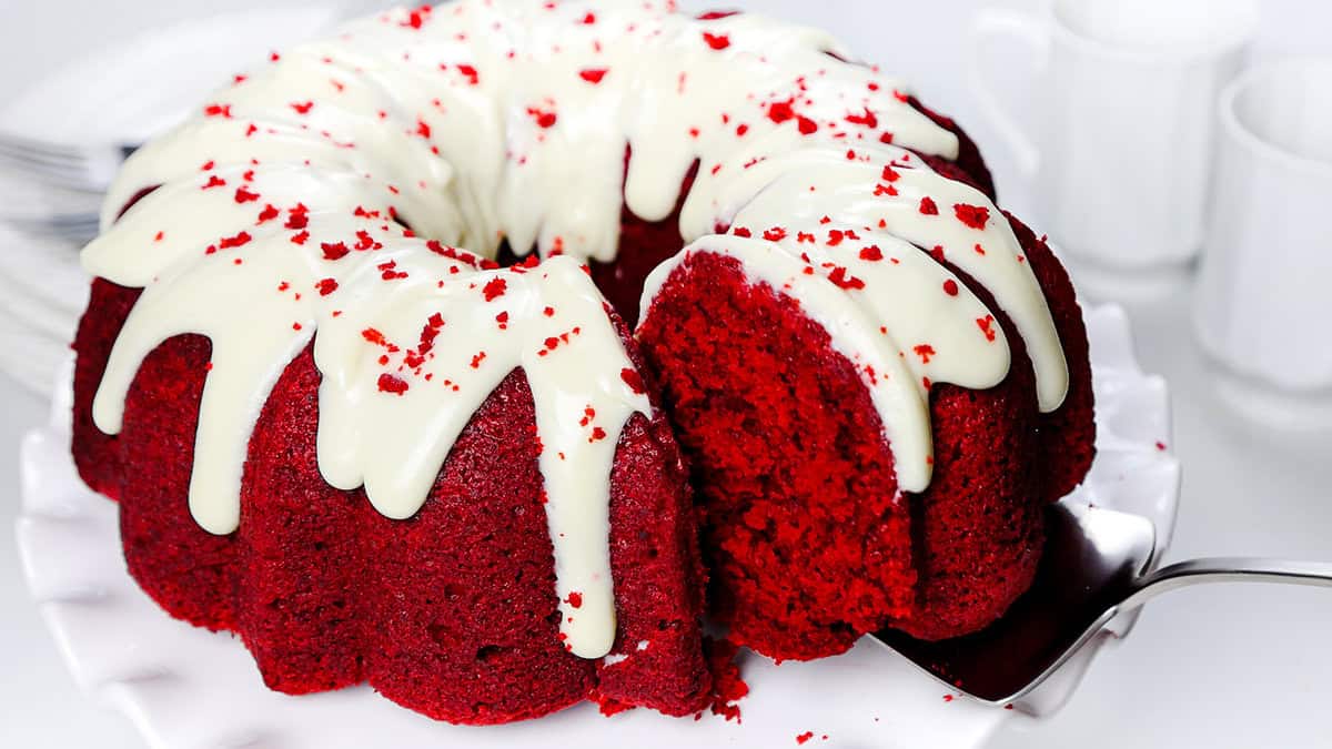 A slice of red velvet Bundt cake being removed with a cake peel.