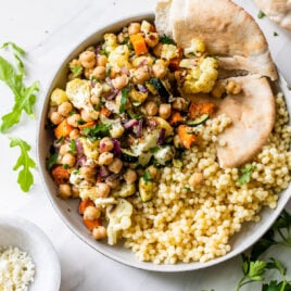 Roasted vegetable salad in a bowl with quinoa and pita bread