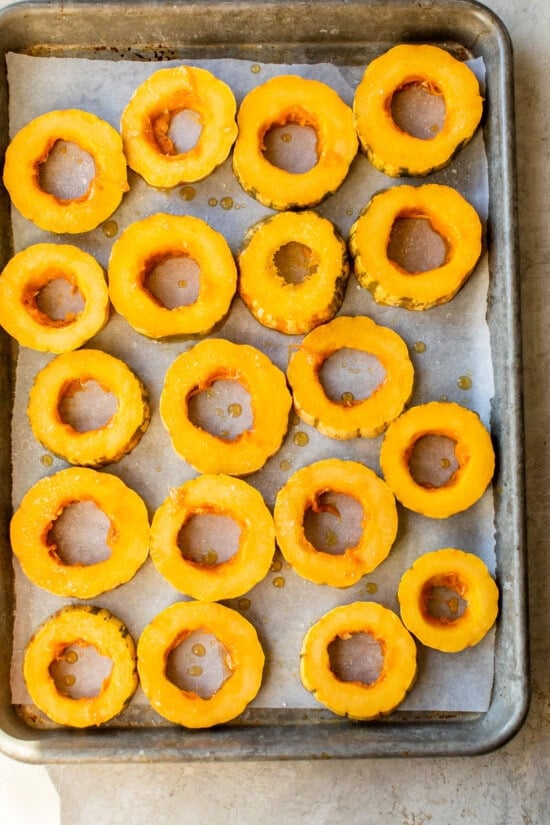 Place the delicata squash on a rimmed baking sheet lined with parchment paper.