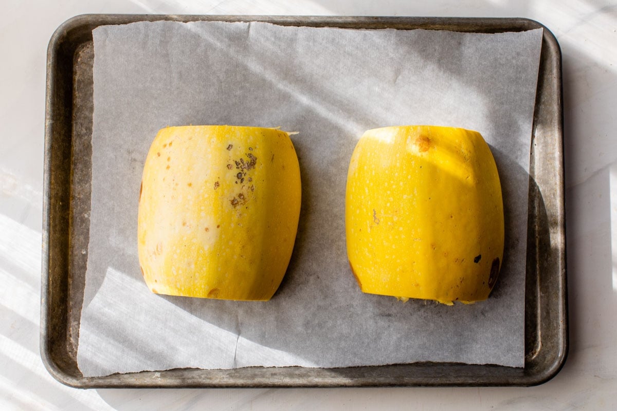 Spaghetti squash cut side down on a baking sheet