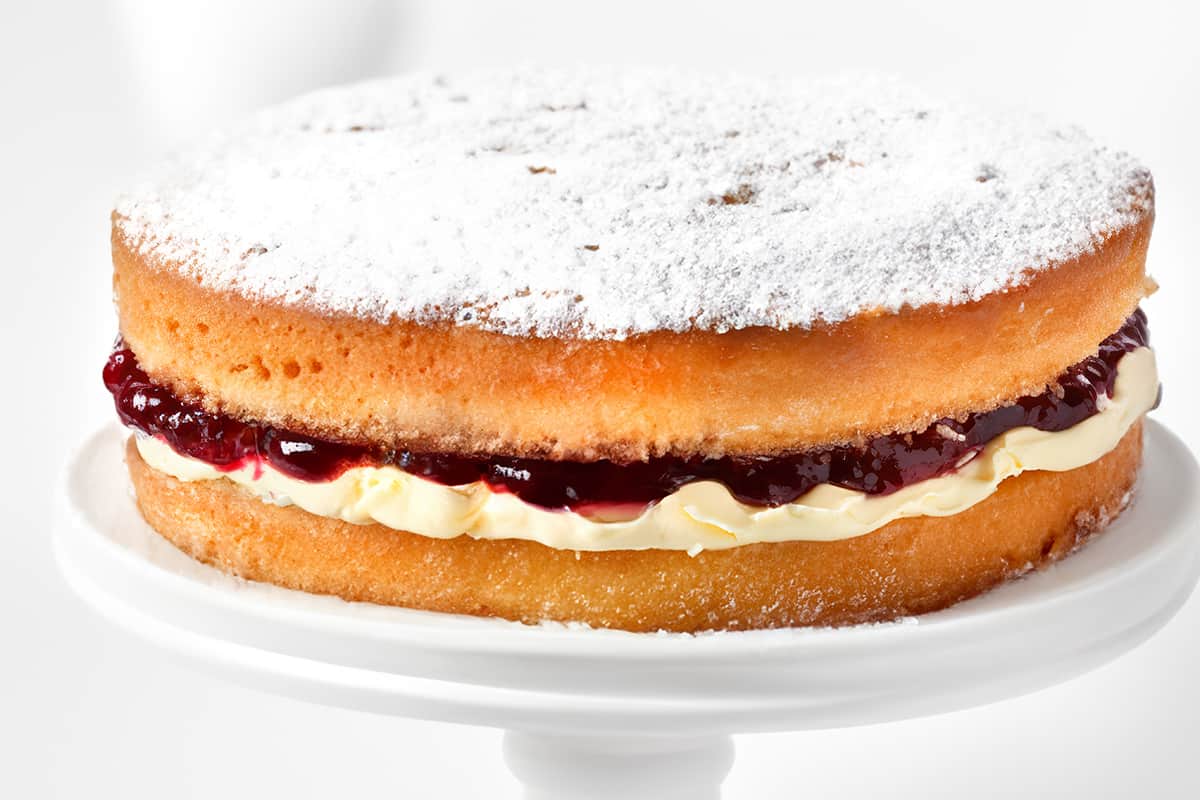 A close up image of a Victoria sponge cake covered in powdered sugar.