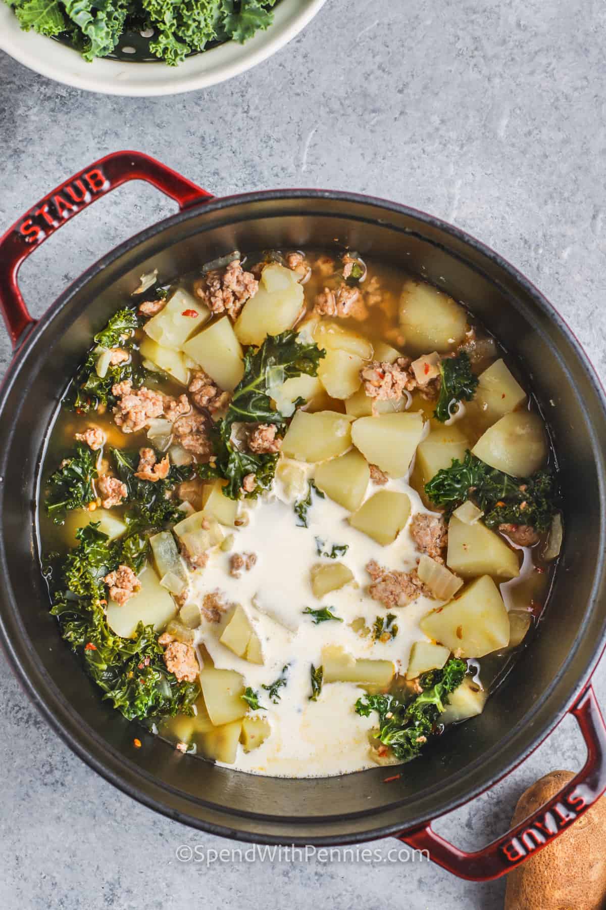 Adding cream to the ingredients to make Zuppa Toscana