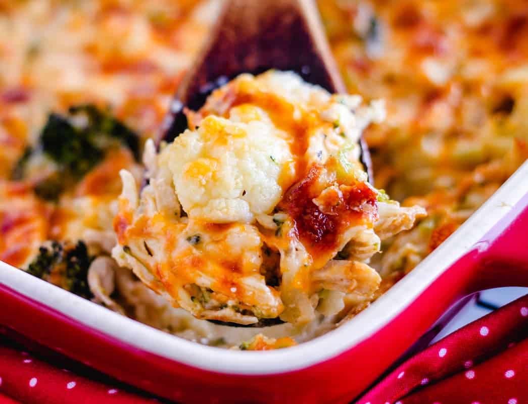 A wooden spoon to scoop out a serving of chicken and cauliflower casserole.