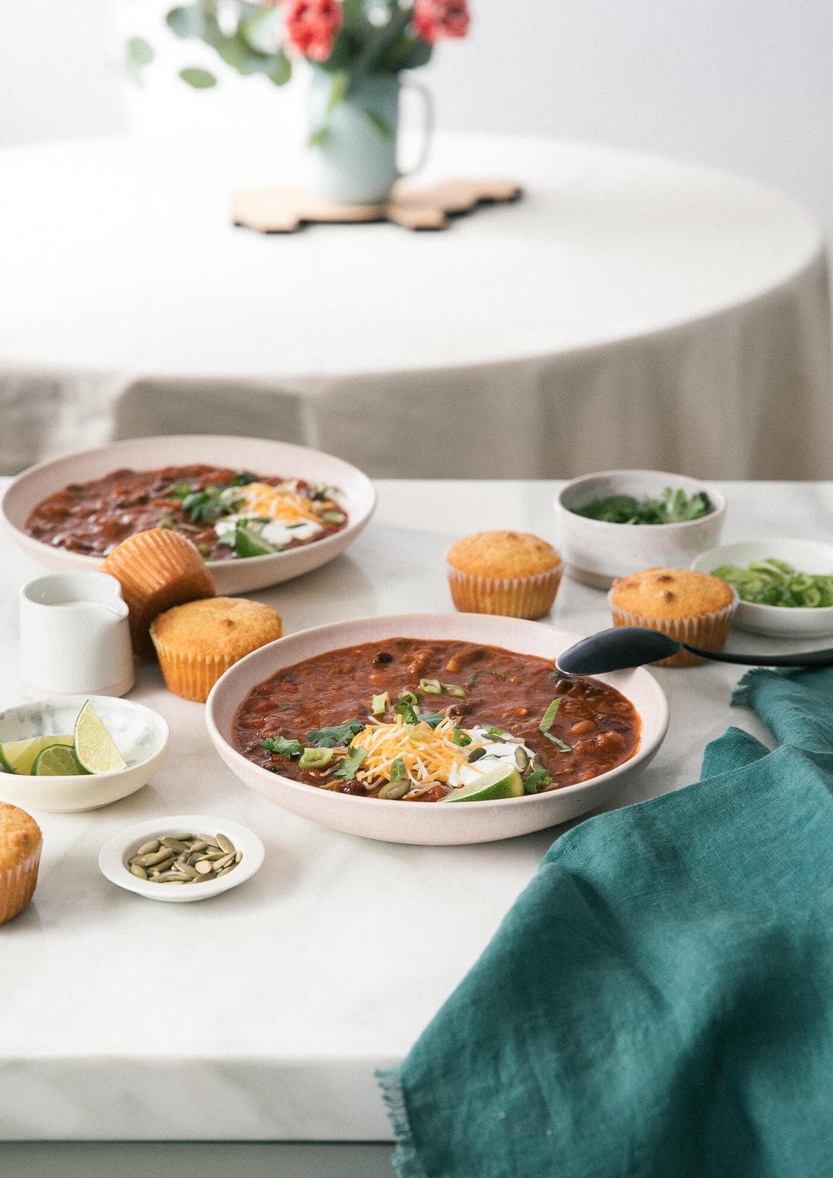 Pumpkin chili on the counter with side dishes and cornbread. 