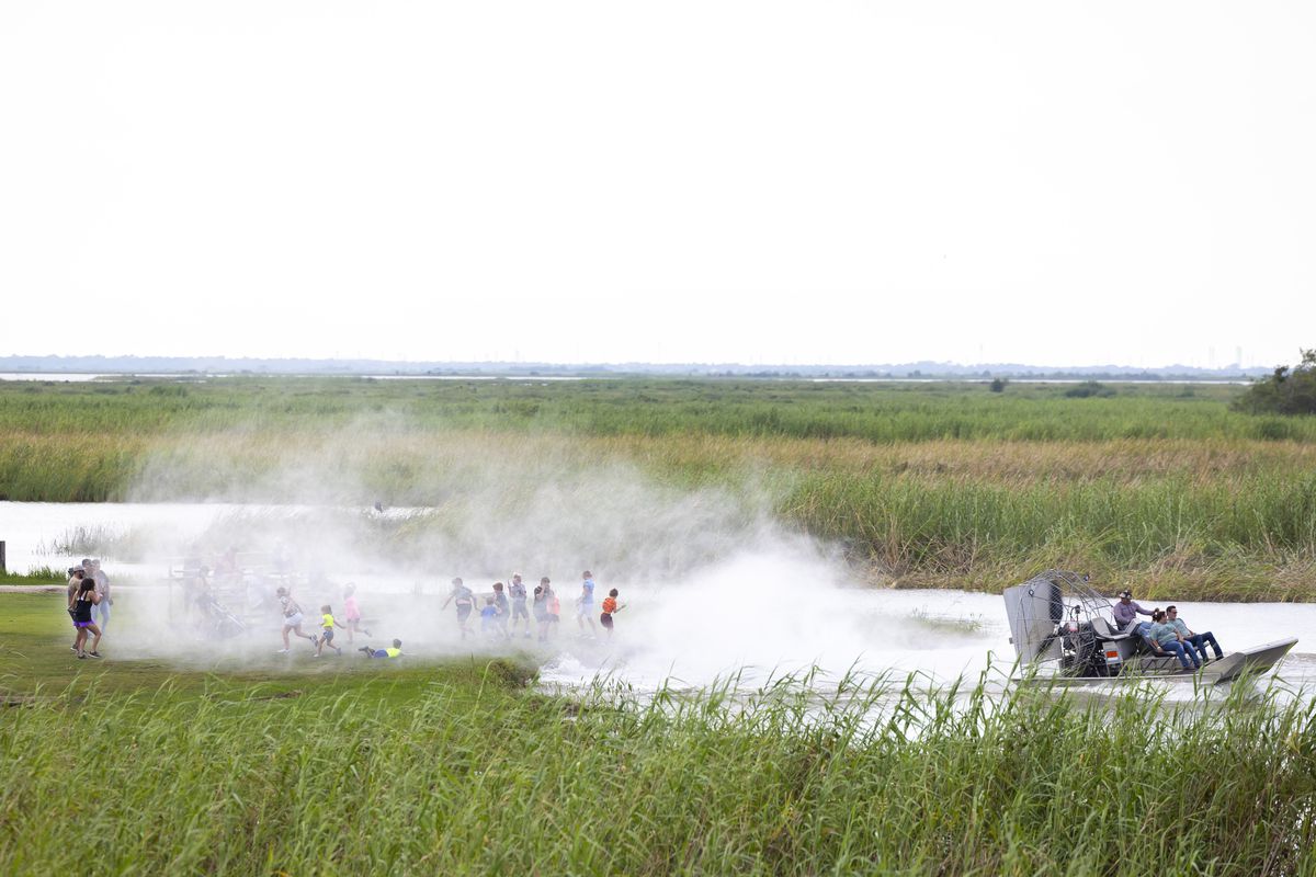 Children on the shore are sprayed with water by airboats at the Texas Gatorfest in Anahuac.