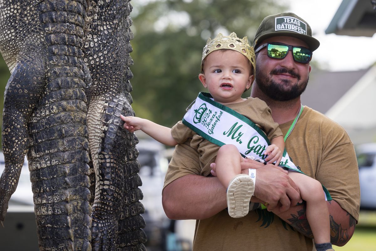 An eighteen-month-old boy poses for a photo with an alligator at GATORFEST Texas in Anahuac.