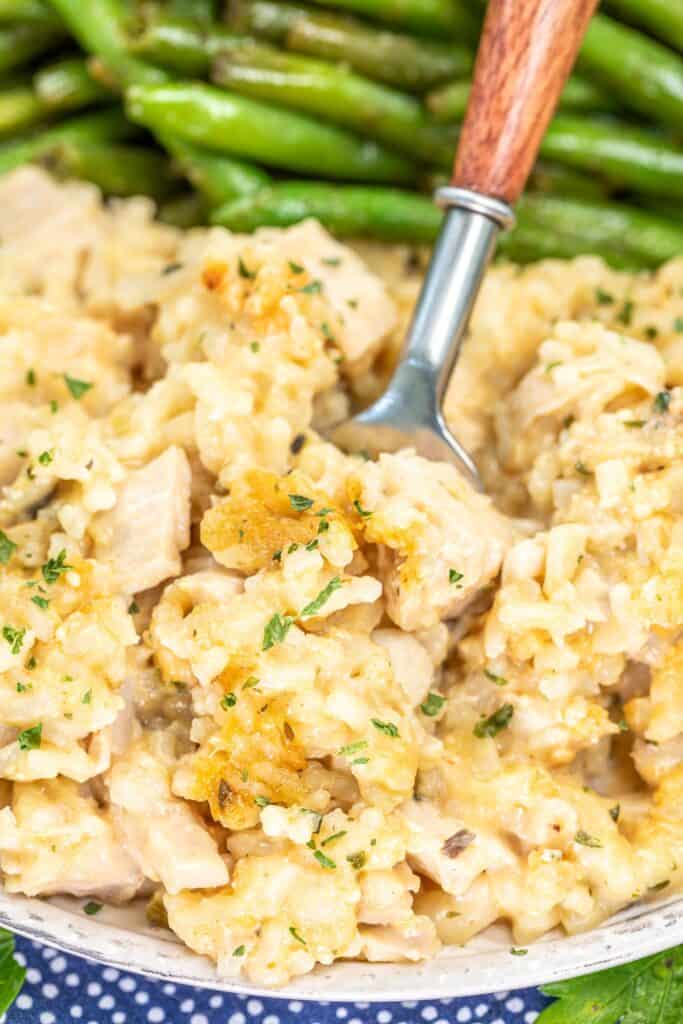 A fork scooping chicken and rice out of a plate. 