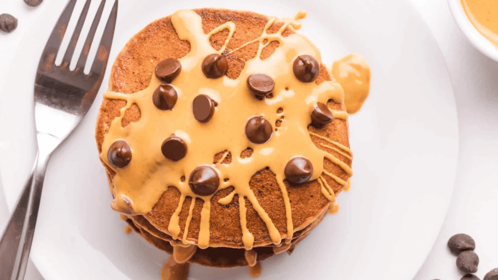 A stack of protein pancakes topped with caramel sauce and chocolate chips.