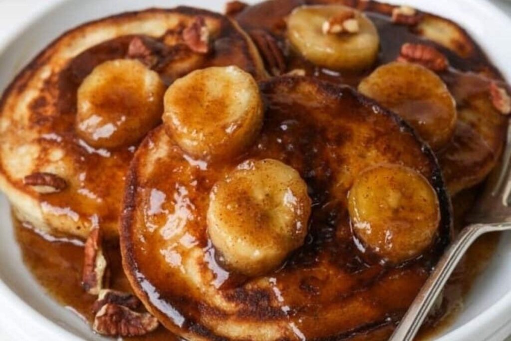 A close up image of Bananas Foster on top of a stack of pancakes. 