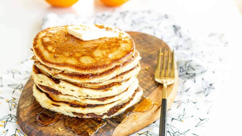 Ricotta and orange pancakes on a wooden board.